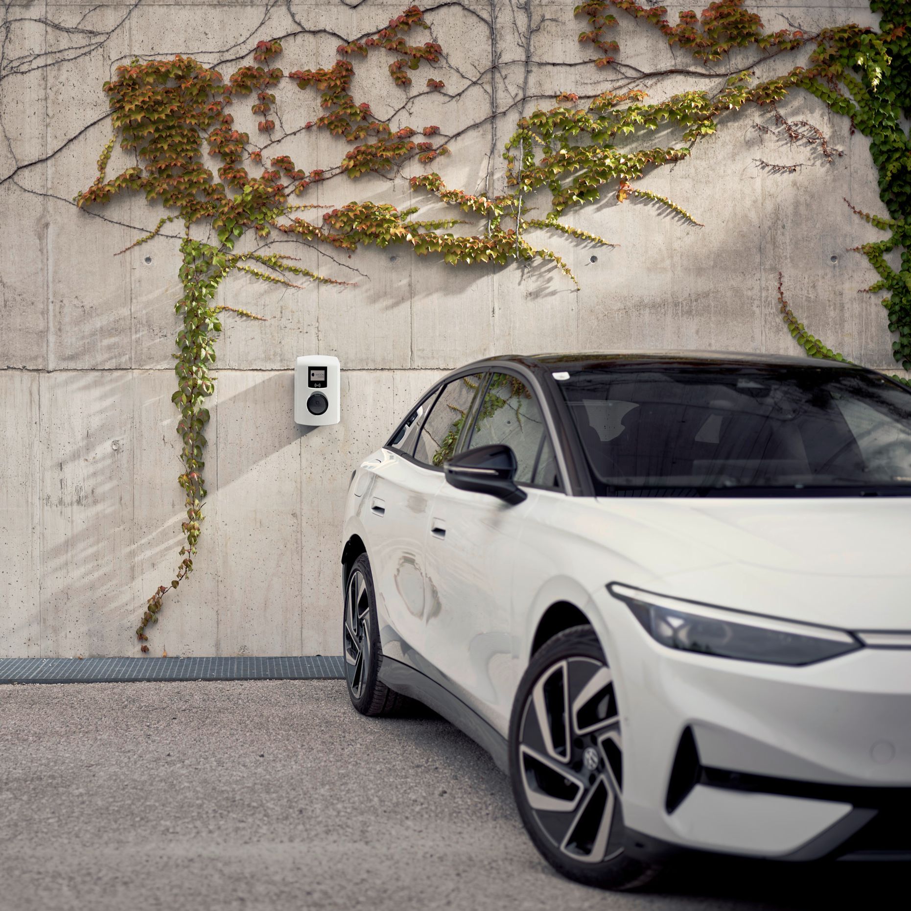 Car stands in front of a concrete wall with wallbox